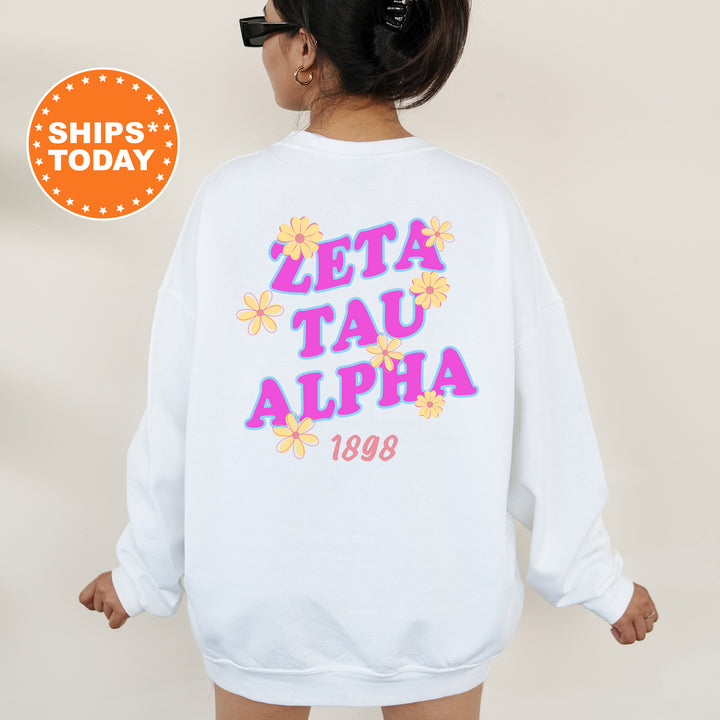 A woman wearing a white sweatshirt with the text "ZETA TAU ALPHA" and "1898" printed on it.