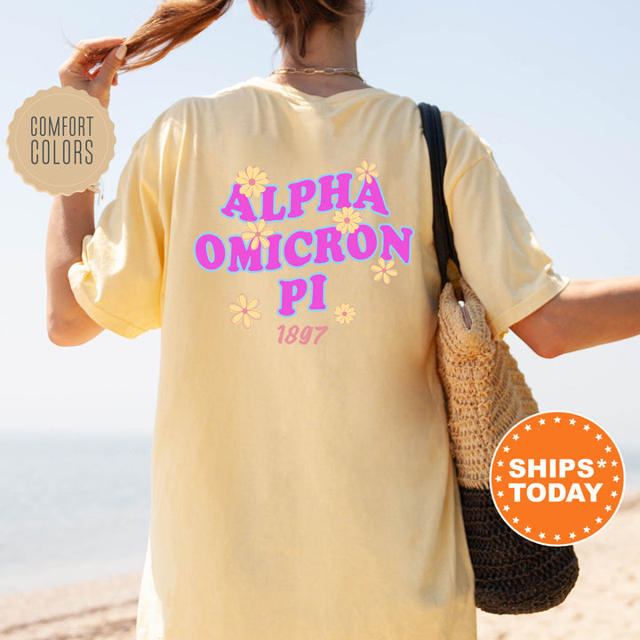 A person wearing a yellow t-shirt with the text "ALPHA OMICRON PI" printed on it, standing on a beach.