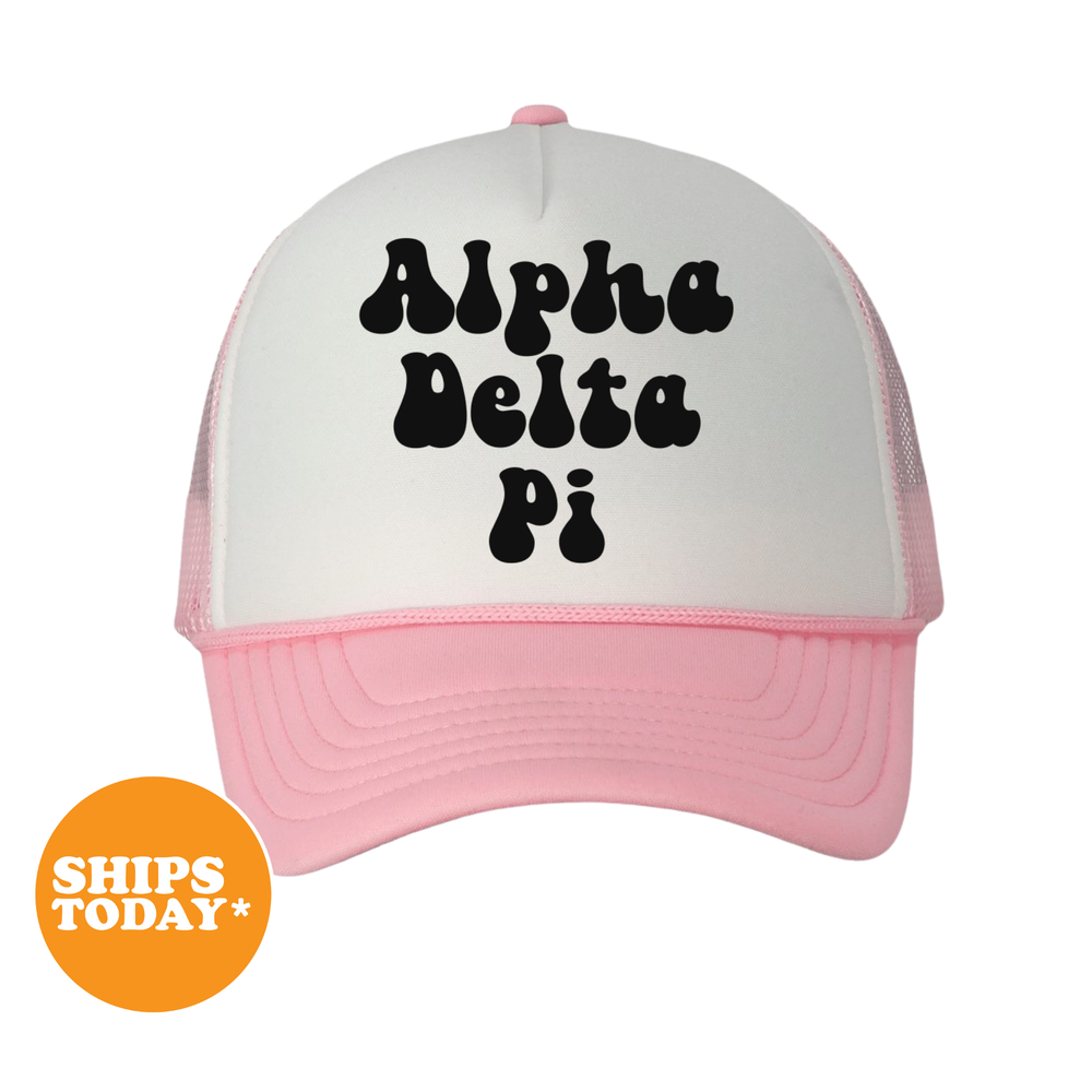 A pink and white baseball cap with the text "Alpha Delta Pi" printed on it.