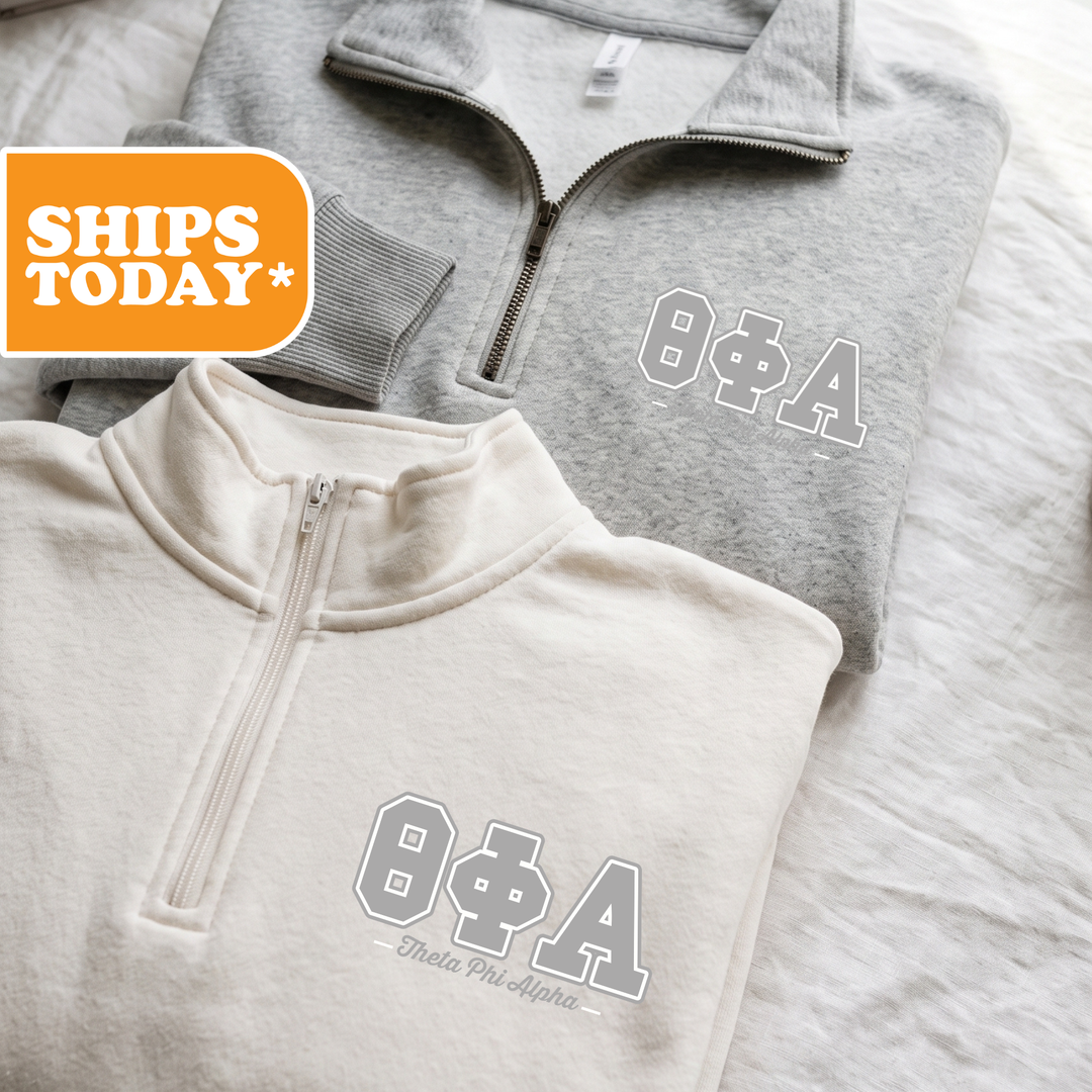 Two gray sweatshirts with white text and logos are displayed on a bed.