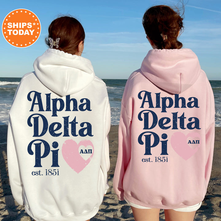 two women wearing pink and white hooded sweatshirts on the beach