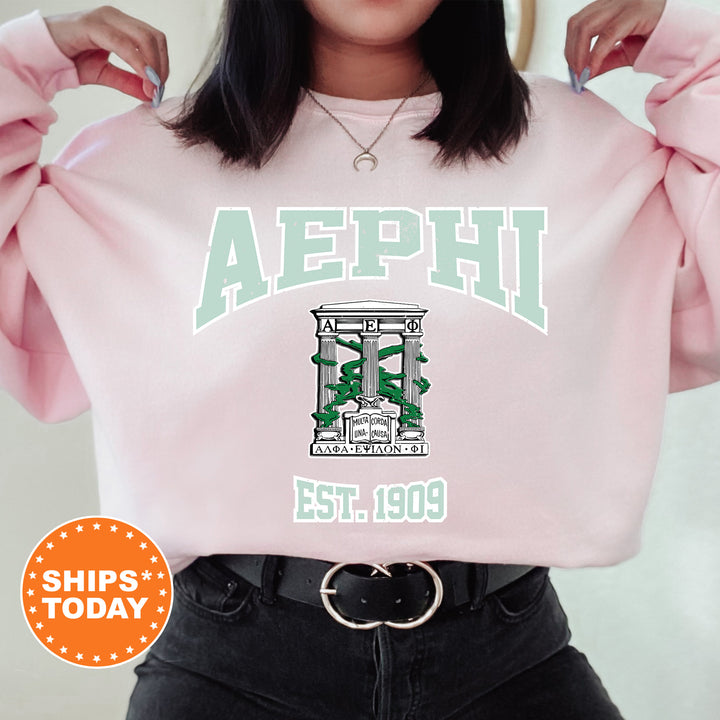 a woman wearing a pink sweatshirt with the letters aephi on it