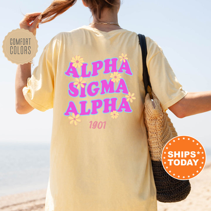 A person wearing a yellow t-shirt with the text "ALPHA SIGMA ALPHA 1901" printed on it, standing on a beach.