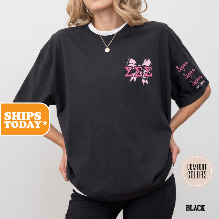 a woman wearing a black shirt with pink bows on it