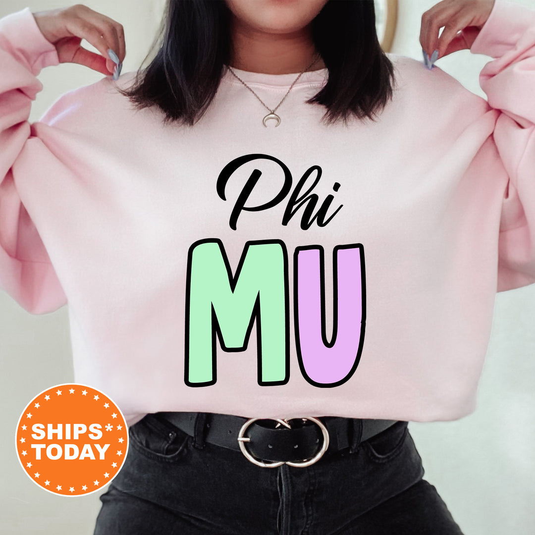 a woman wearing a pink sweatshirt with the word phi mu on it