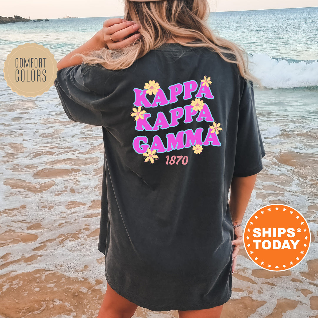 A woman wearing a black t-shirt with the text "KAPPAKGAMA" printed on it, standing on a beach with waves in the background.