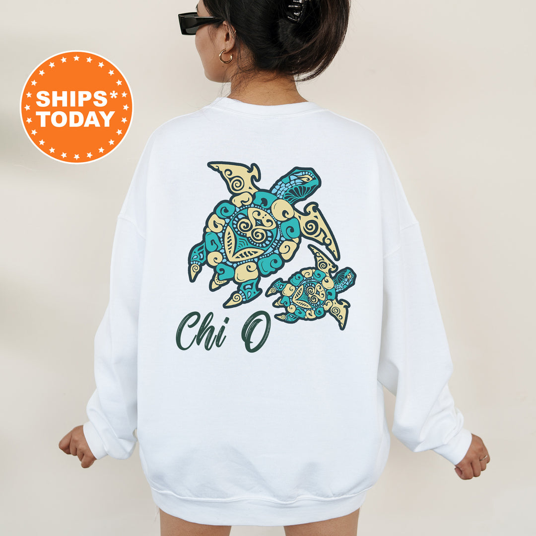 A woman wearing a white sweatshirt with a colorful graphic of a turtle and the text "Chi O" printed on it.