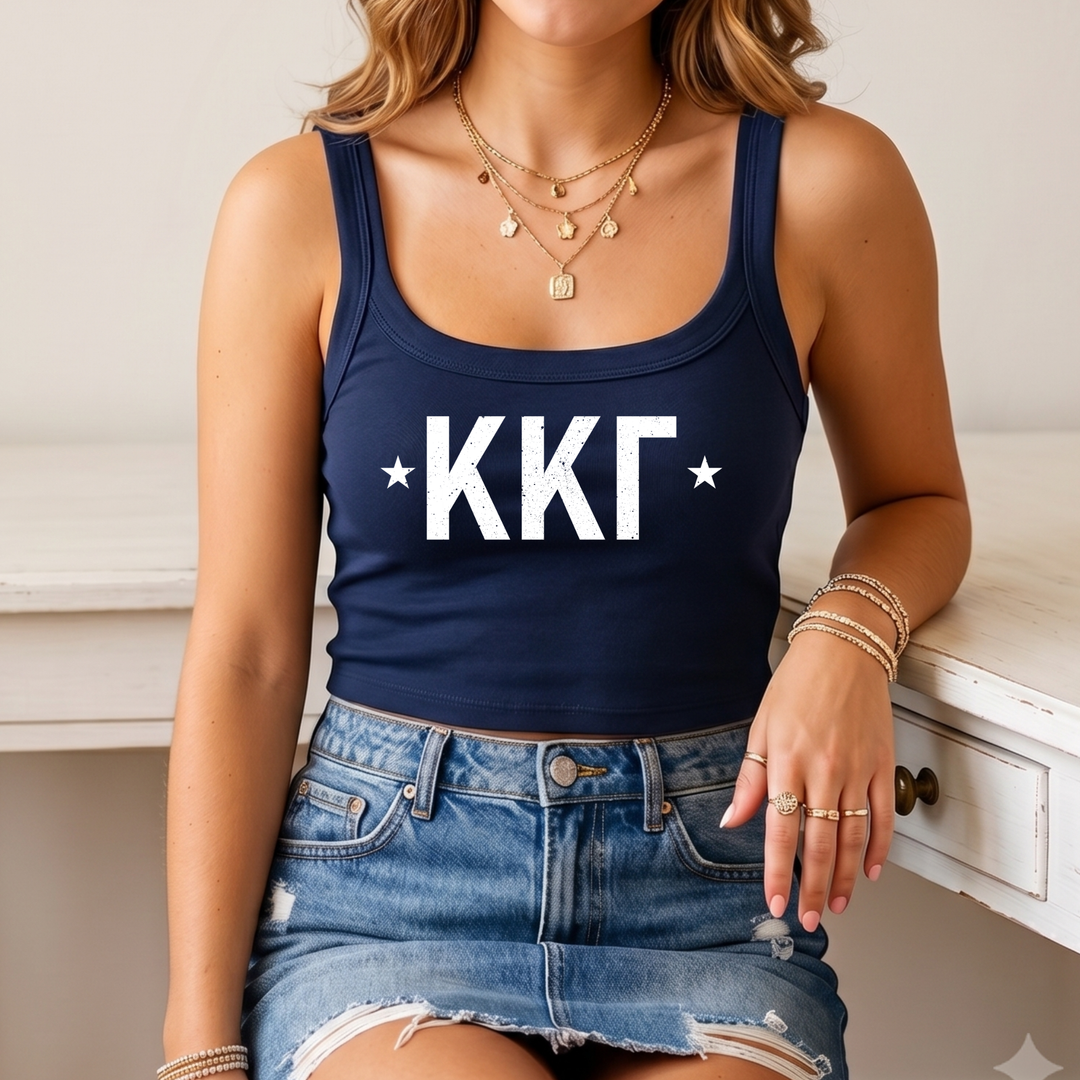 A woman wearing a navy blue crop top with white text and a denim skirt, sitting on a white surface.