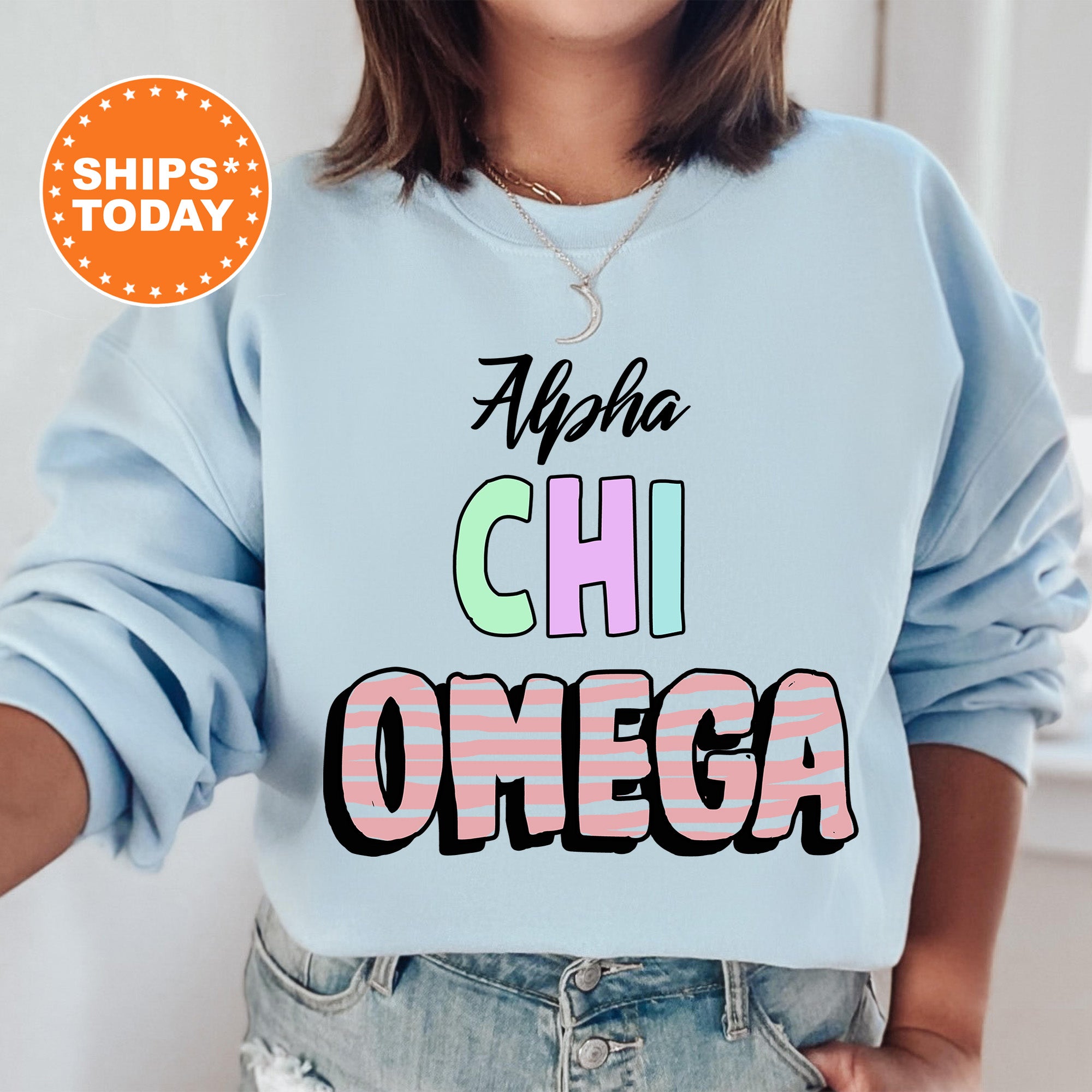 a woman wearing a light blue sweatshirt with the words ahha chi omega on it