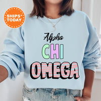 a woman wearing a light blue sweatshirt with the words ahha chi omega on it