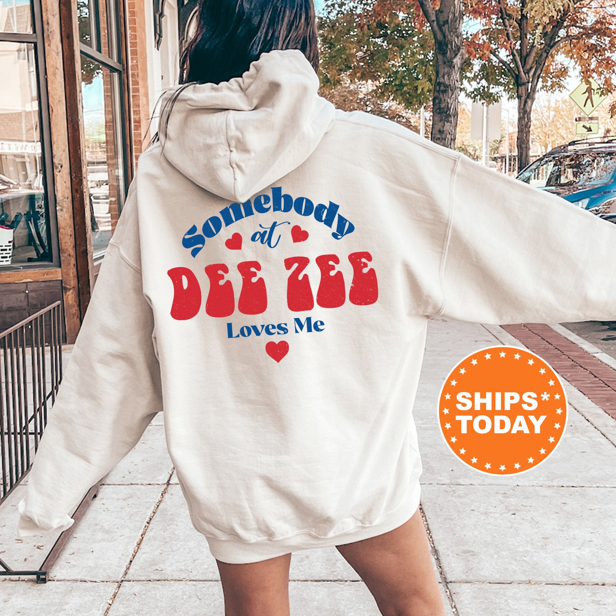 a woman walking down a sidewalk wearing a white hoodie
