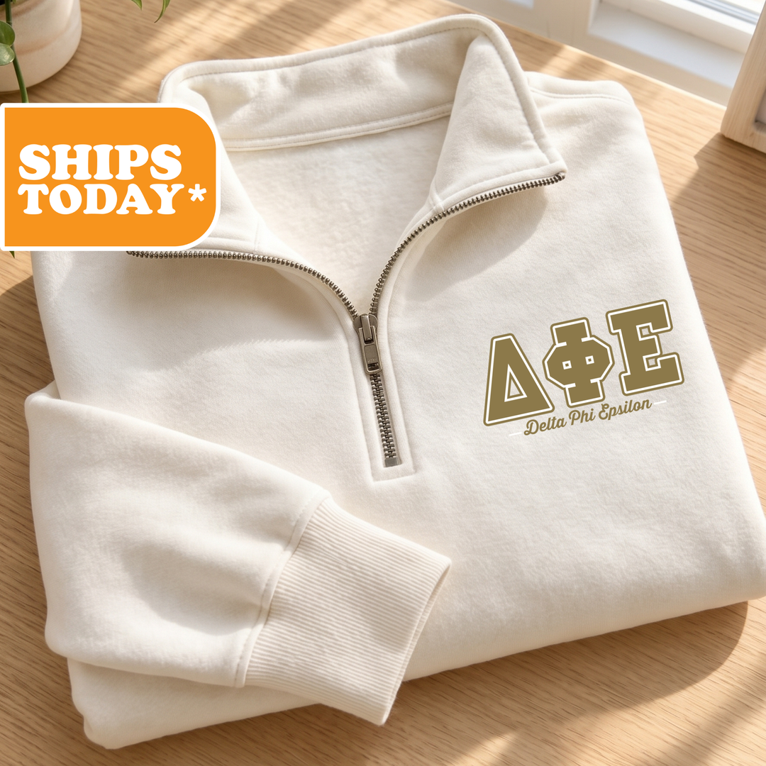 A white fleece jacket with a zipper and the letters "ΔΕΛΙΑΣ" printed on the front, placed on a wooden surface.