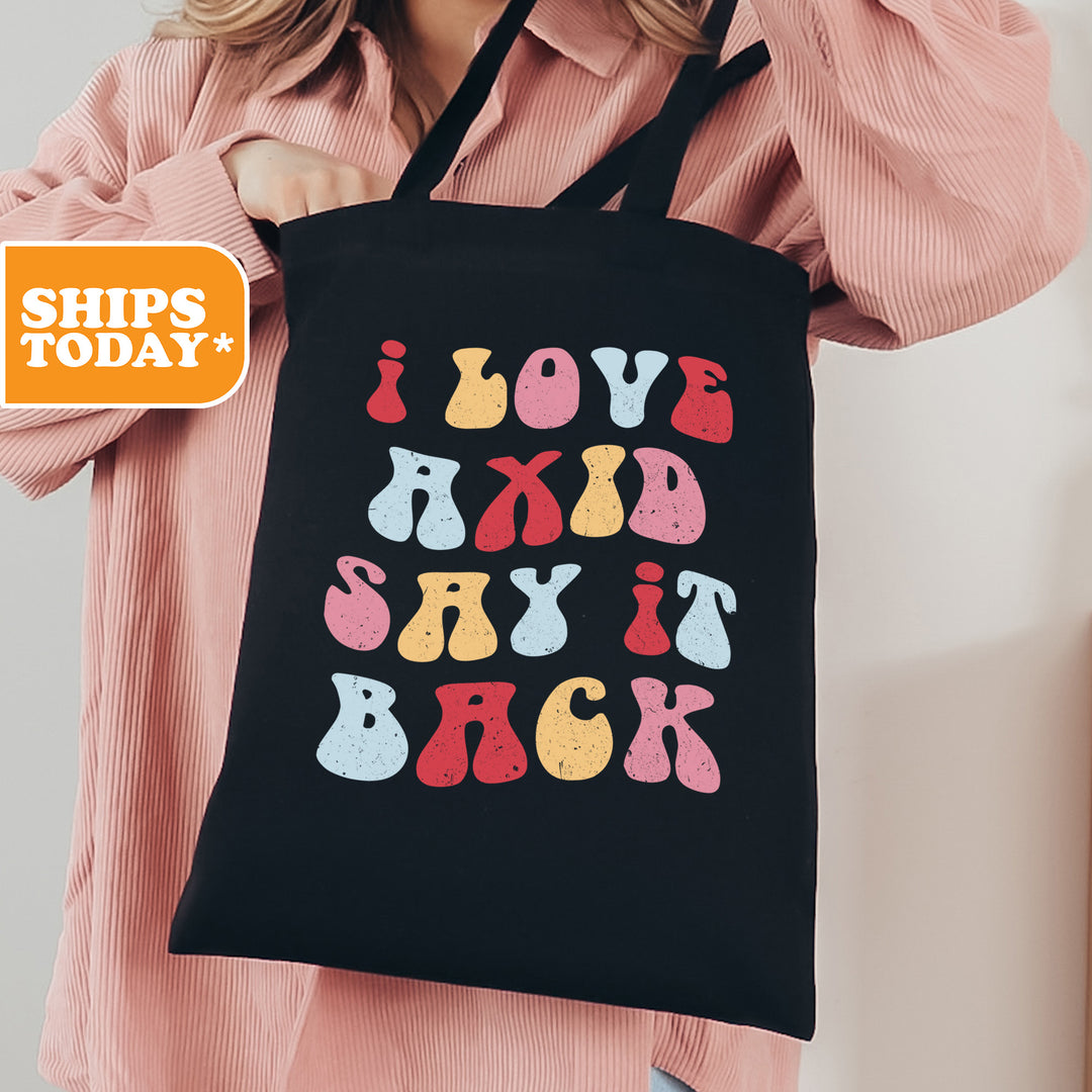 a woman holding a black shopping bag that says i love my kid and say it
