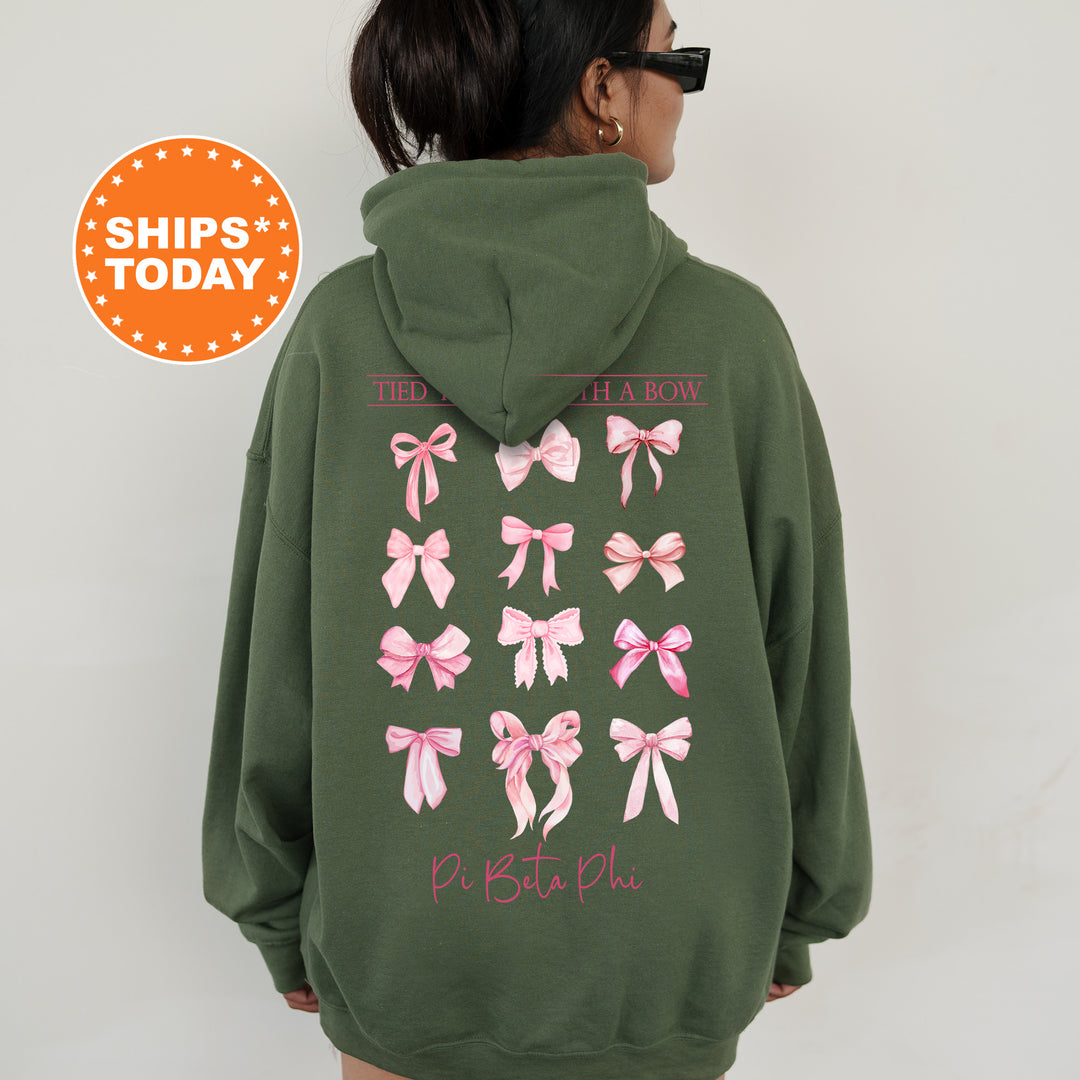 A person wearing a green hoodie with pink bows printed on it, standing against a white background.