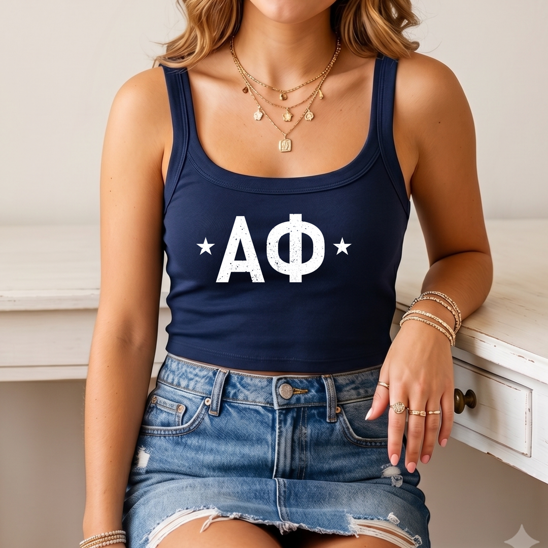 A woman wearing a navy blue crop top with white text and a denim skirt, sitting on a white desk.
