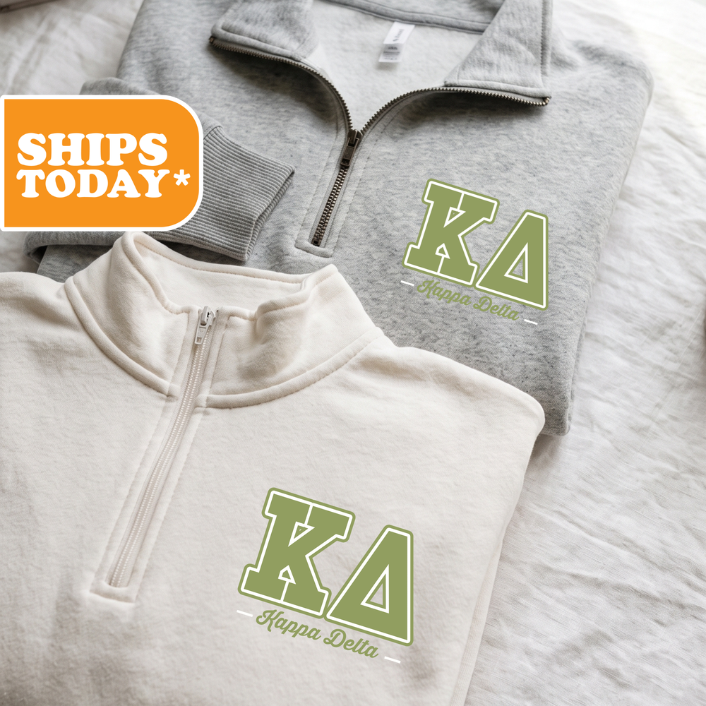 Two gray sweatshirts with the Kappa Delta logo are displayed on a bed, with a shipping label visible in the top left corner.