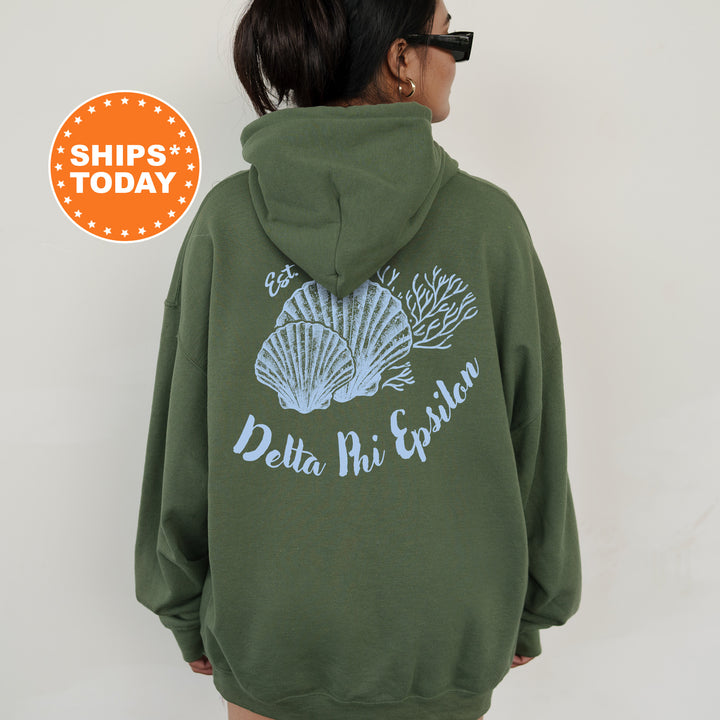 A person wearing a green hoodie with a graphic of seashells and the text "Delta Phi Epsilon" printed on the back.