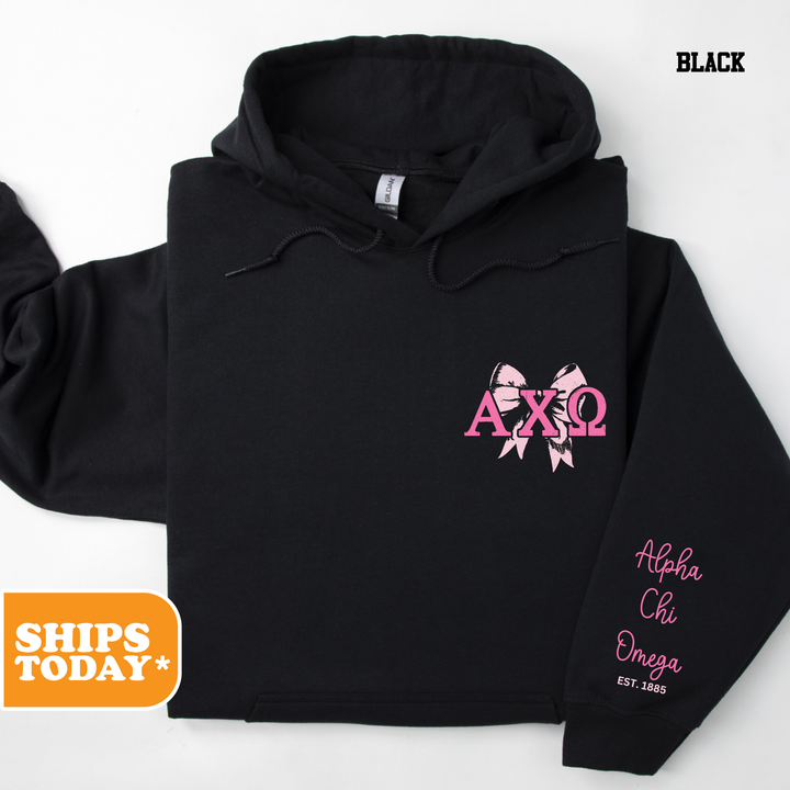 a black hoodie with pink letters and a pink bow