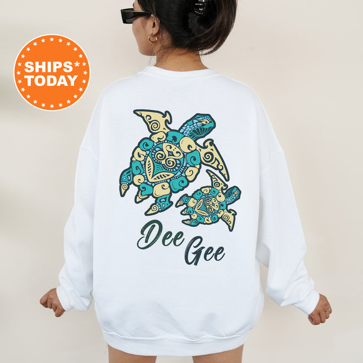 A woman wearing a white sweatshirt with a colorful turtle design and the name "Dee Gee" printed on it.