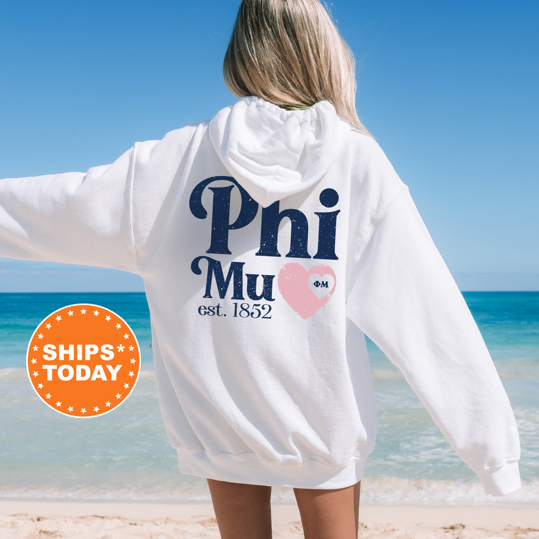 a woman standing on a beach wearing a white hoodie