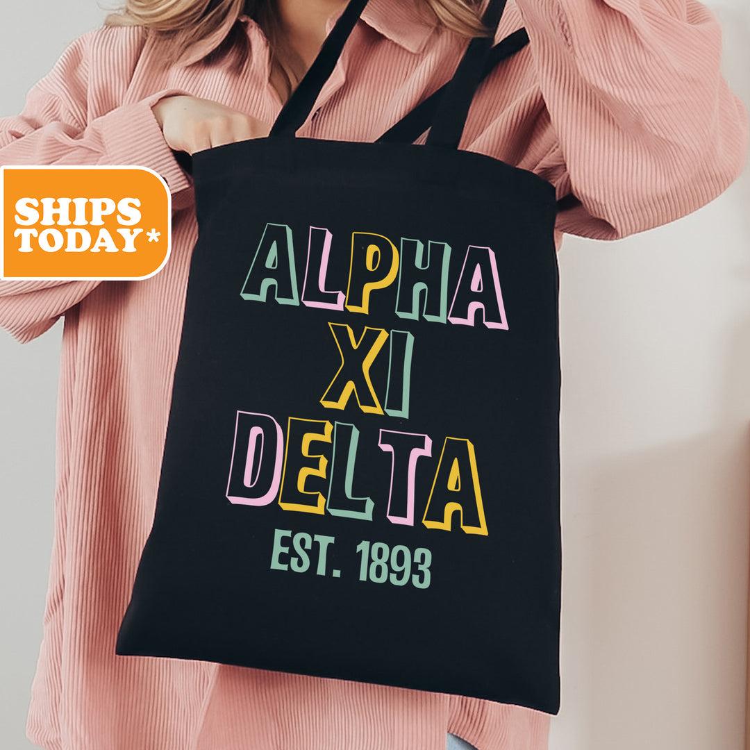 a woman holding a black tote bag with the words, alpha xi delta est