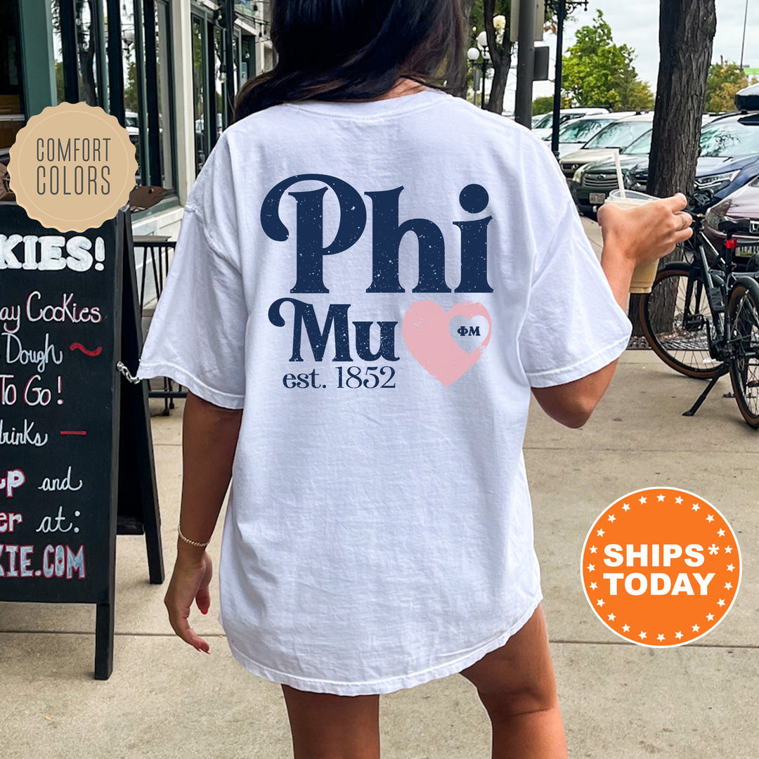 a woman walking down a sidewalk while wearing a phi mu t - shirt