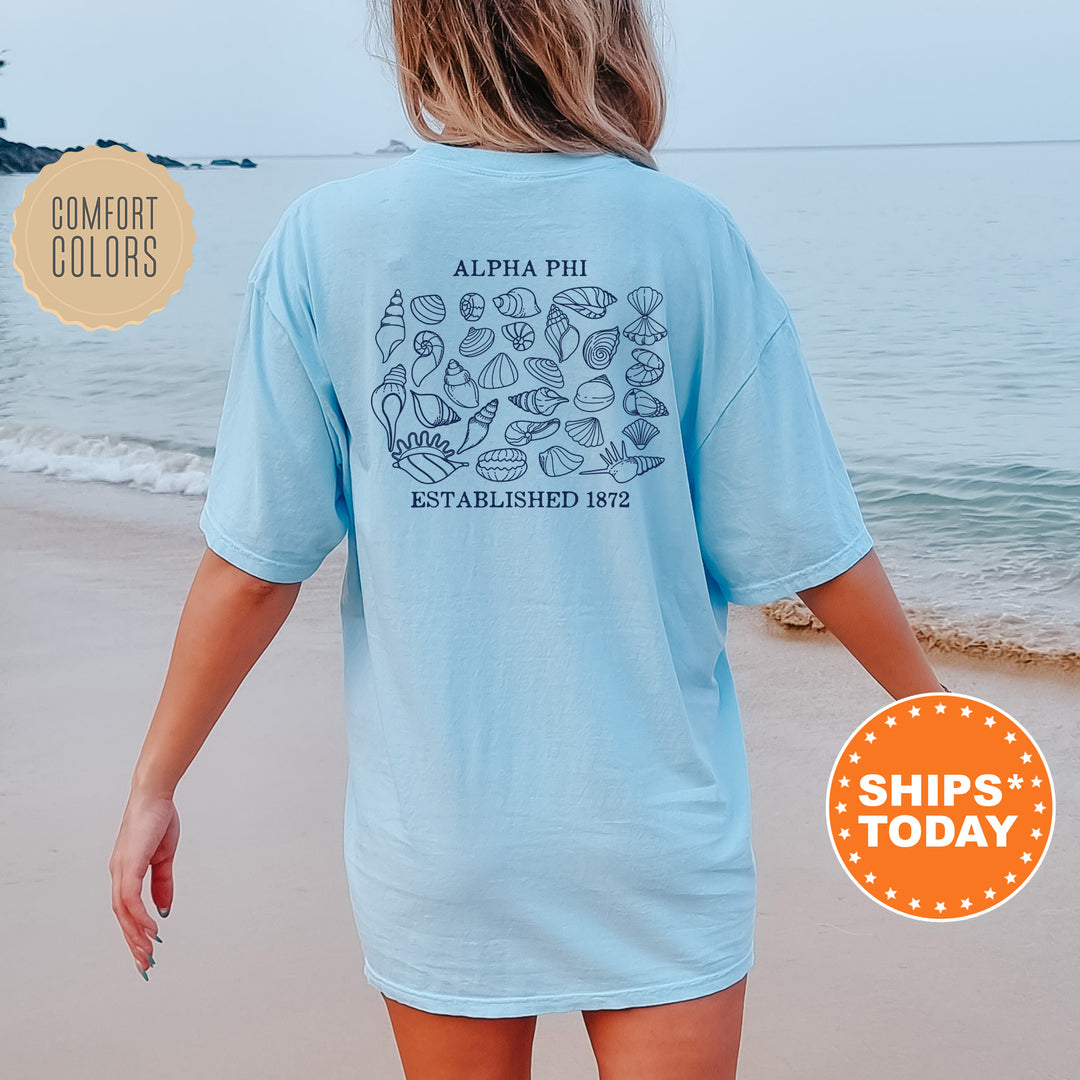 a woman walking on the beach wearing a blue shirt