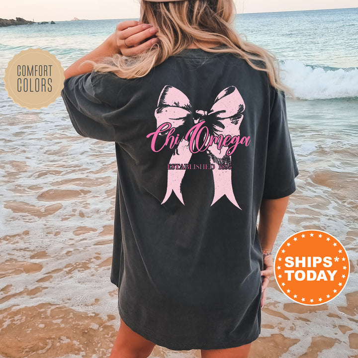 a woman standing on a beach wearing a black shirt with a pink ribbon