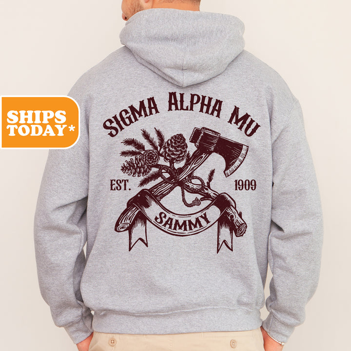 a man wearing a gray hoodie with a hammer and pine tree on it