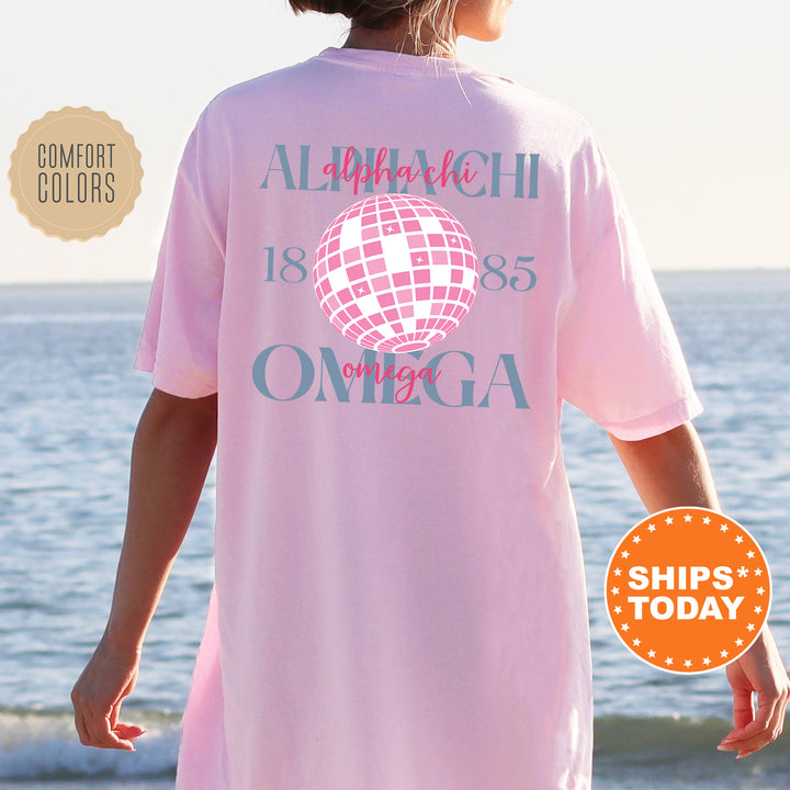 a woman standing on the beach wearing a pink shirt