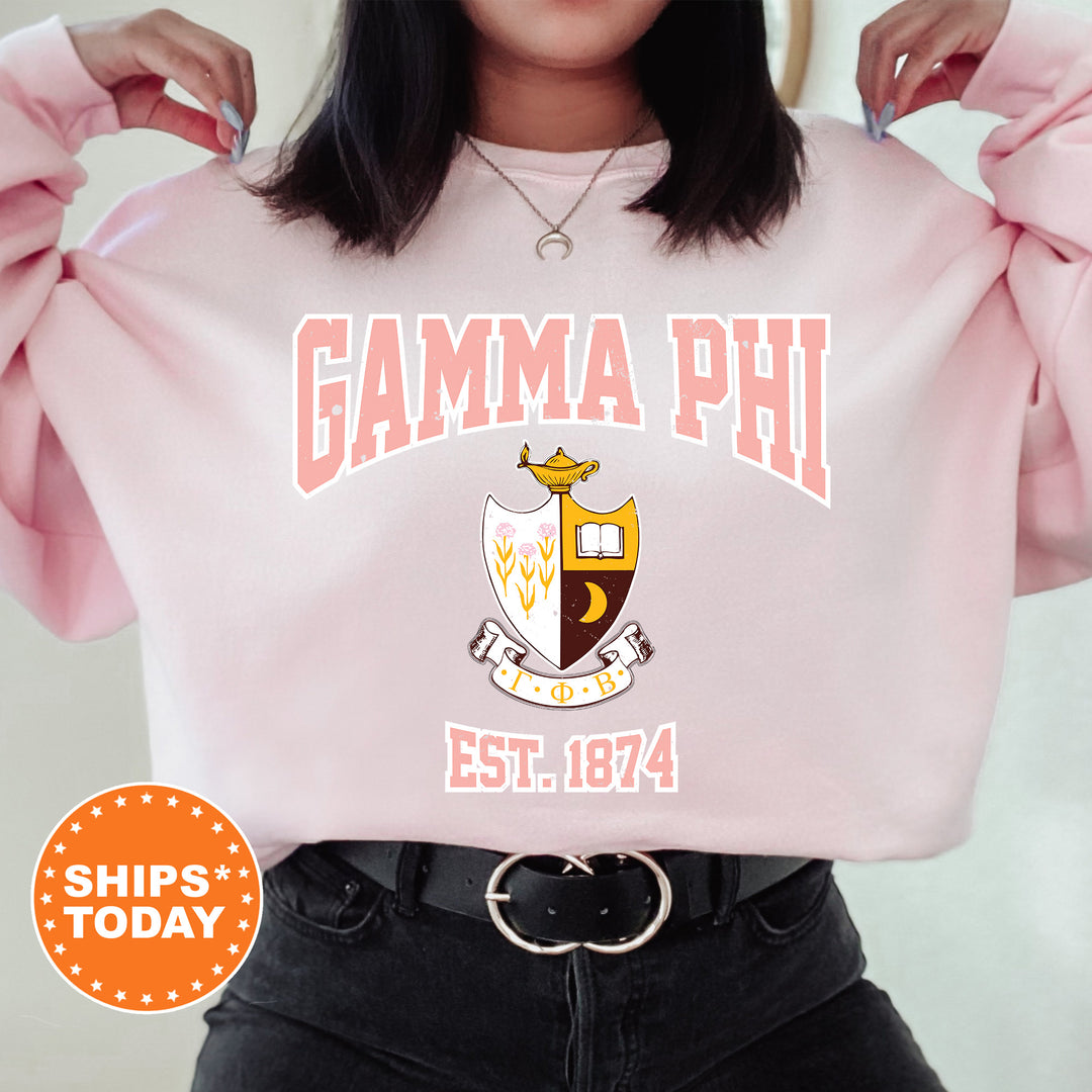 a woman wearing a pink sweatshirt with the words gama phi on it