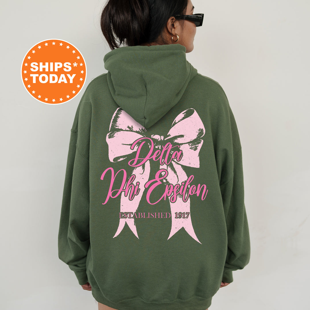 a woman wearing a green sweatshirt with a pink bow on it