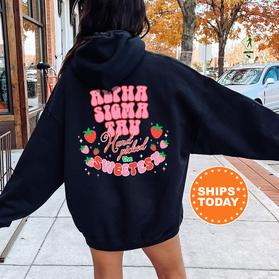 a woman walking down a sidewalk wearing a black hoodie
