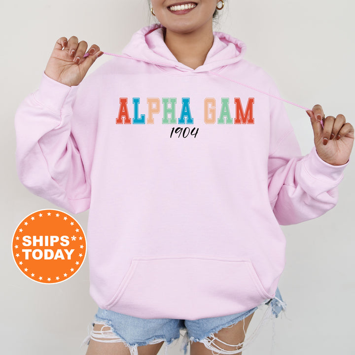 a woman wearing a pink hoodie with the word alpha gam printed on