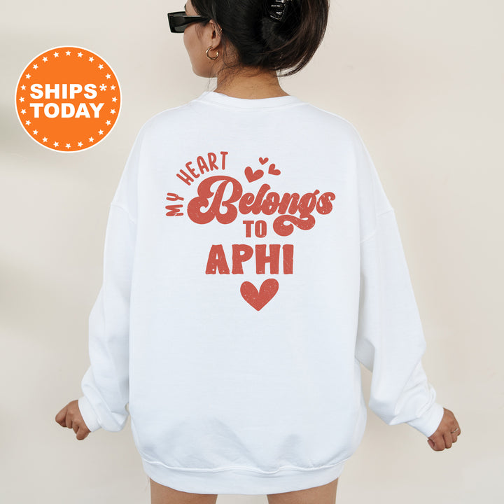 a woman wearing a white sweatshirt with the words heart belongs to aphi on it