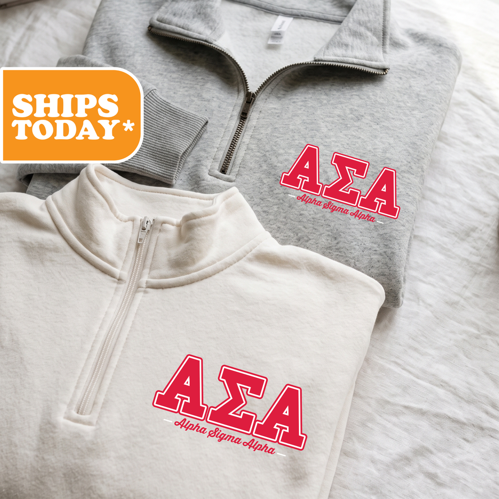 Two gray sweatshirts with red text and logos, one white and one gray, are displayed on a bed.