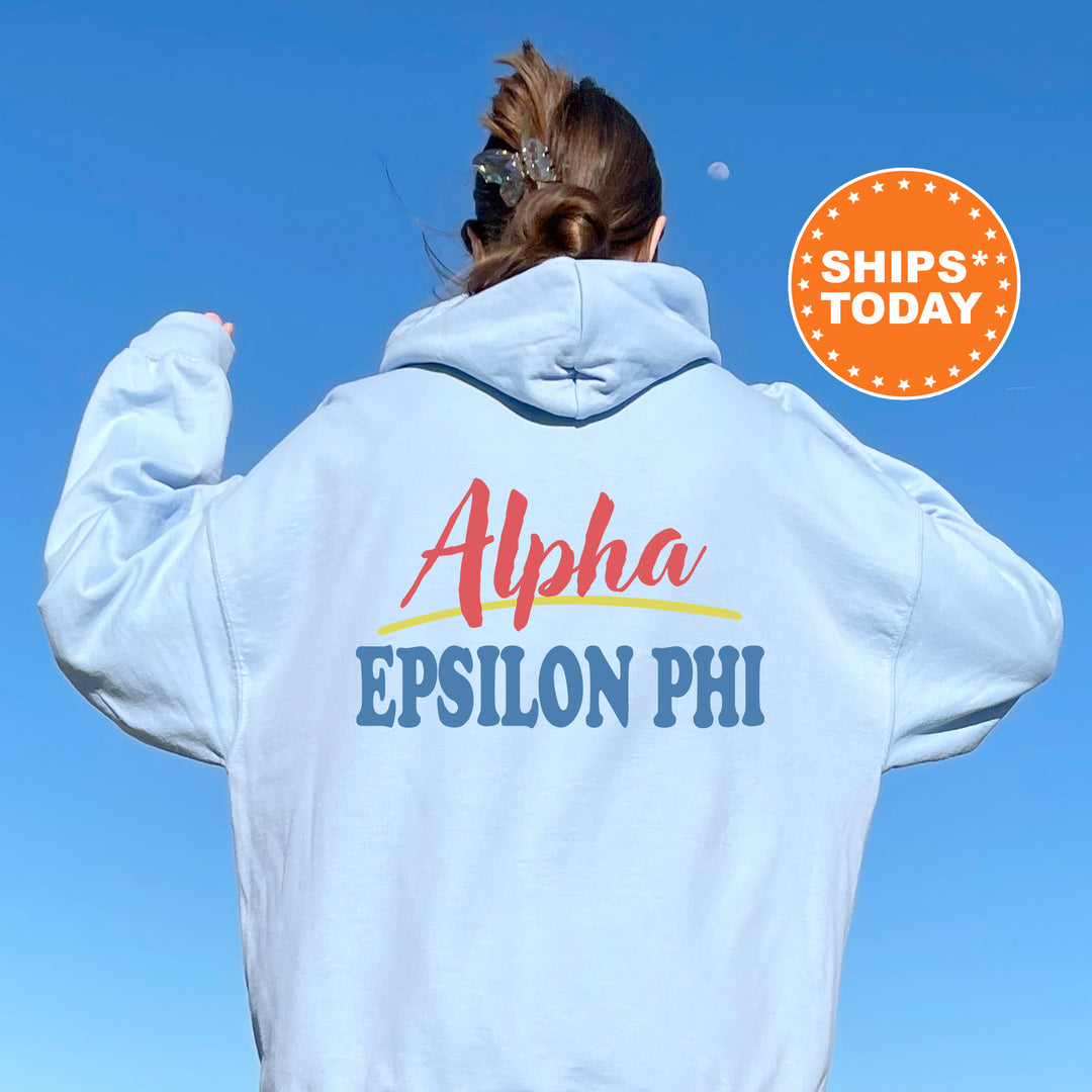 A person wearing a white hoodie with the text "Alpha Epsilon Phi" printed on it, standing against a clear blue sky.
