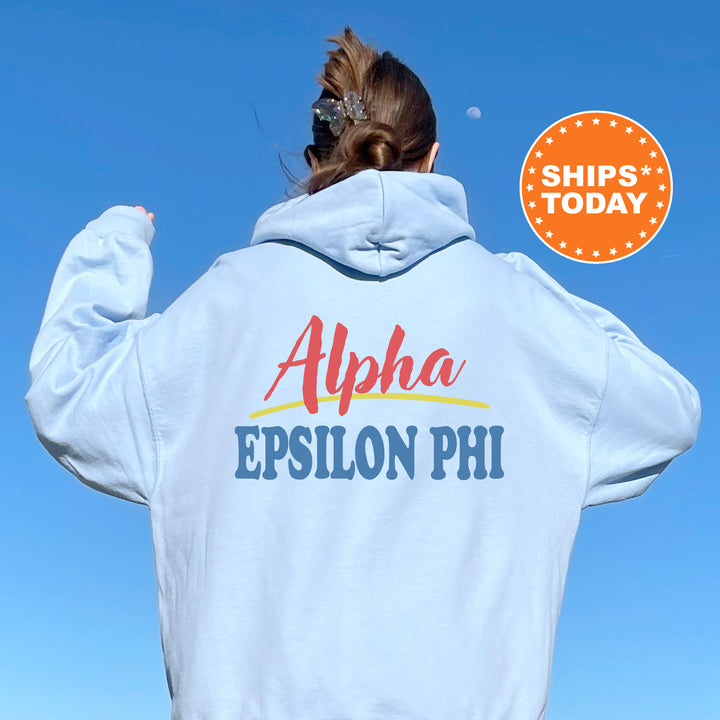 A person wearing a white hoodie with the text "Alpha Epsilon Phi" printed on it, standing against a clear blue sky.