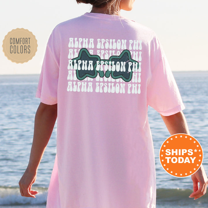 a woman standing on a beach wearing a pink shirt