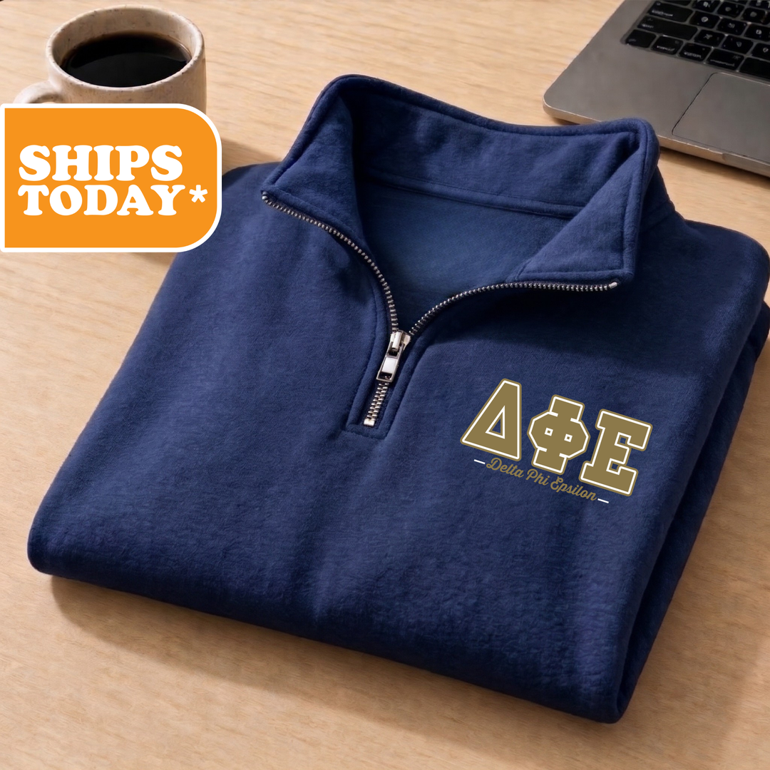A navy blue zip-up jacket with the letters 'ΦΕΛΙΑΣ' printed on it, along with a laptop and a coffee cup on a wooden surface.