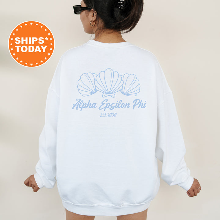 A person wearing a white sweatshirt with a graphic design of three seashells and text that reads "Alpha Epsilon Phi Est. 2009".