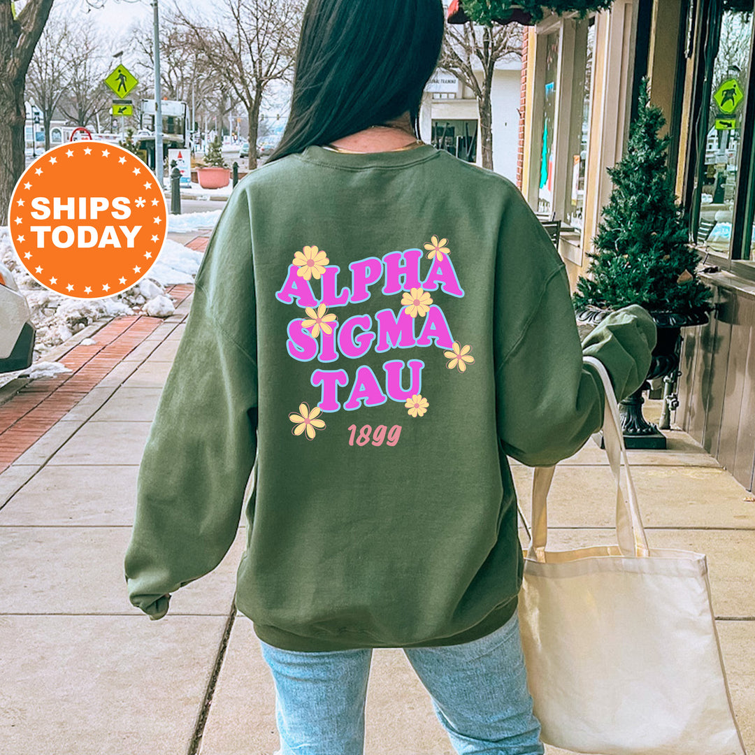 A person wearing a green sweatshirt with the text "ALPHASIGMA TAU" printed on it, walking down a city street.