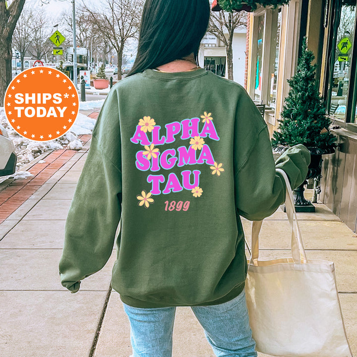 A person wearing a green sweatshirt with the text "ALPHASIGMA TAU" printed on it, walking down a city street.