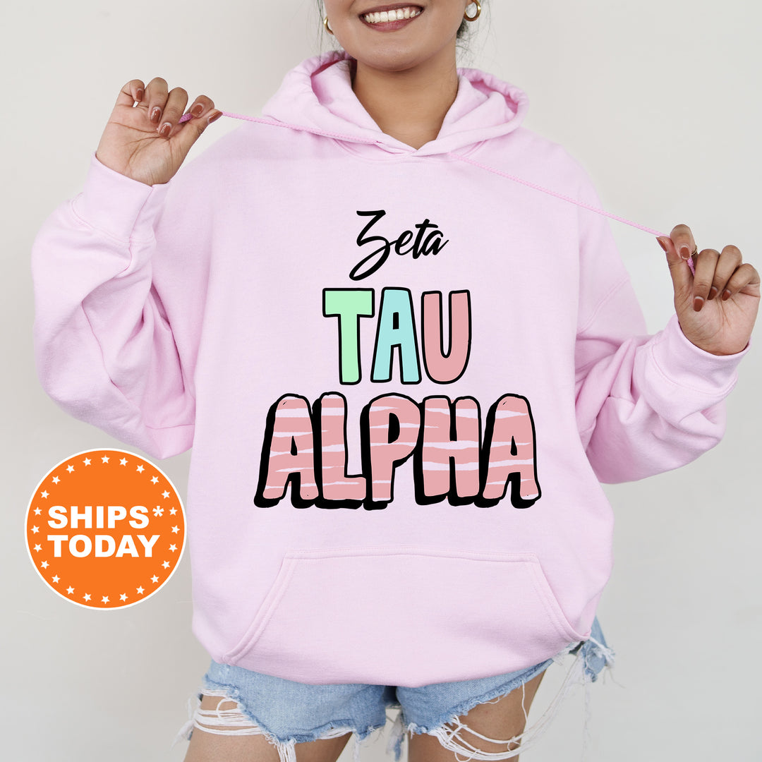 a woman wearing a pink hoodie with the word tau alpha printed on it