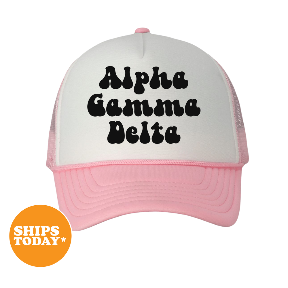 A white and pink baseball cap with the text "Alpha Delta" printed on it.