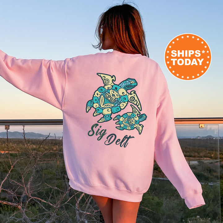 A woman wearing a pink sweatshirt with a graphic of a turtle and the text "Sign Delt" is standing on a balcony overlooking a scenic landscape.