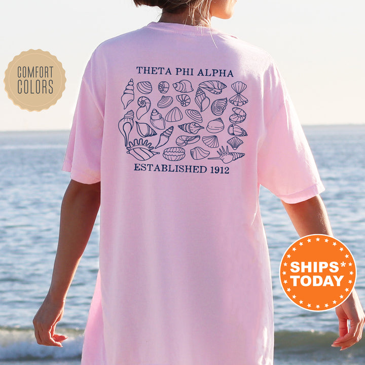 a woman standing on a beach wearing a pink shirt