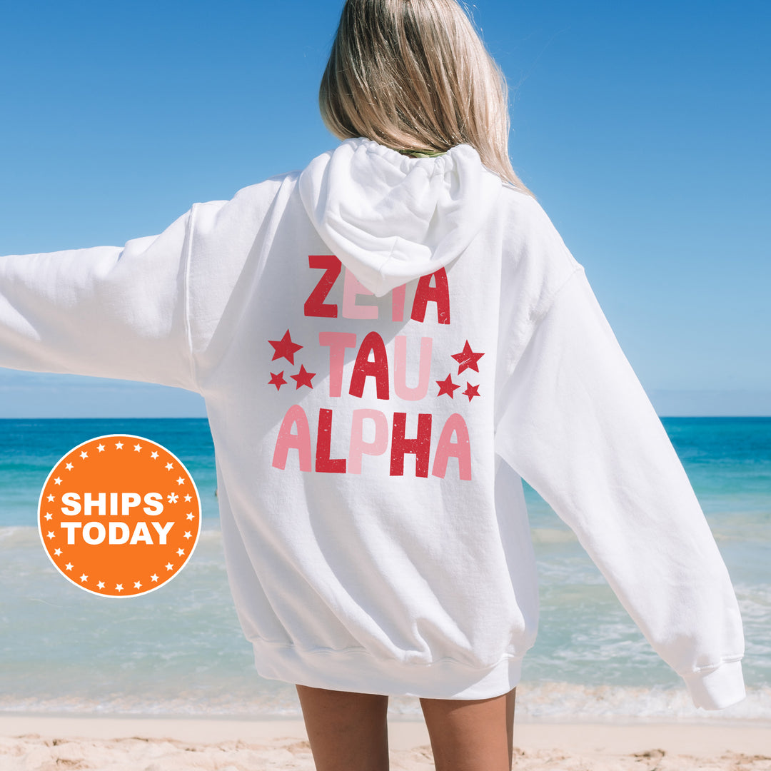 a woman standing on a beach wearing a white hoodie