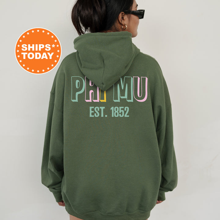 a woman wearing a green hoodie with the words primu est 1932 printed on