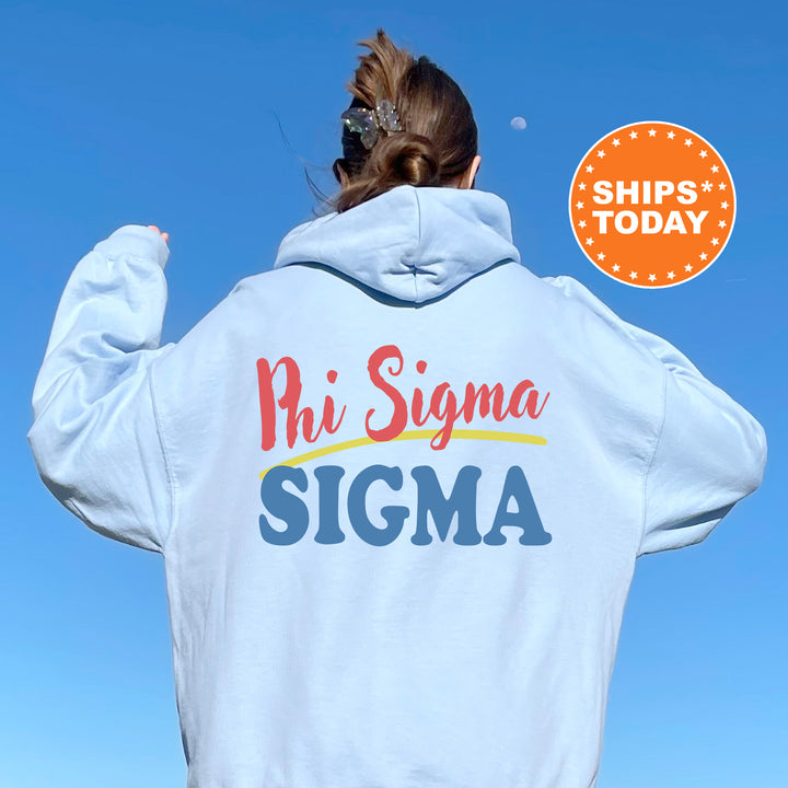 A person wearing a white hoodie with the text "Phi Sigma Sigma" printed on it, standing against a clear blue sky.
